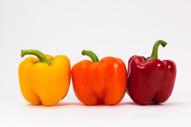 poivrons jaunes orange et rouges posés sur fond blanc