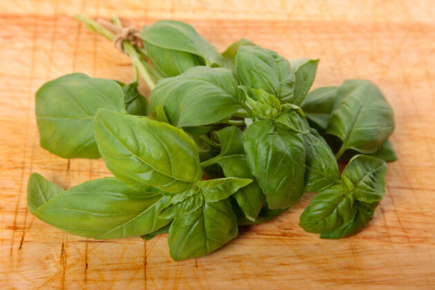 un bouquet de basilic frais sur une planche à découper